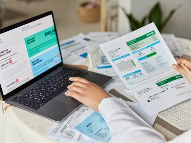 Reviewing invoices and financial statements on a laptop